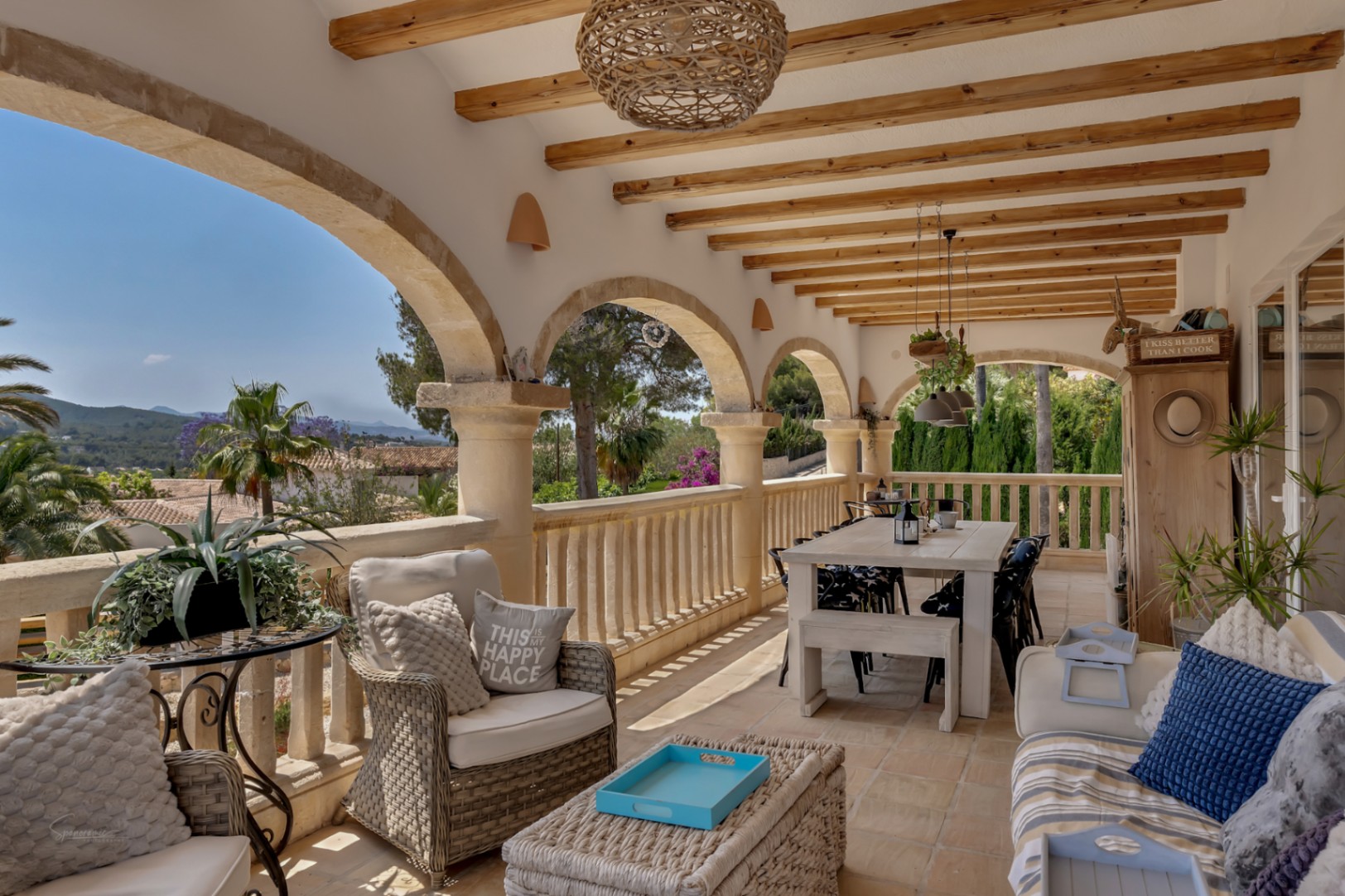 Covered terrace with stone arches, wooden beams, and panoramic mountain views.