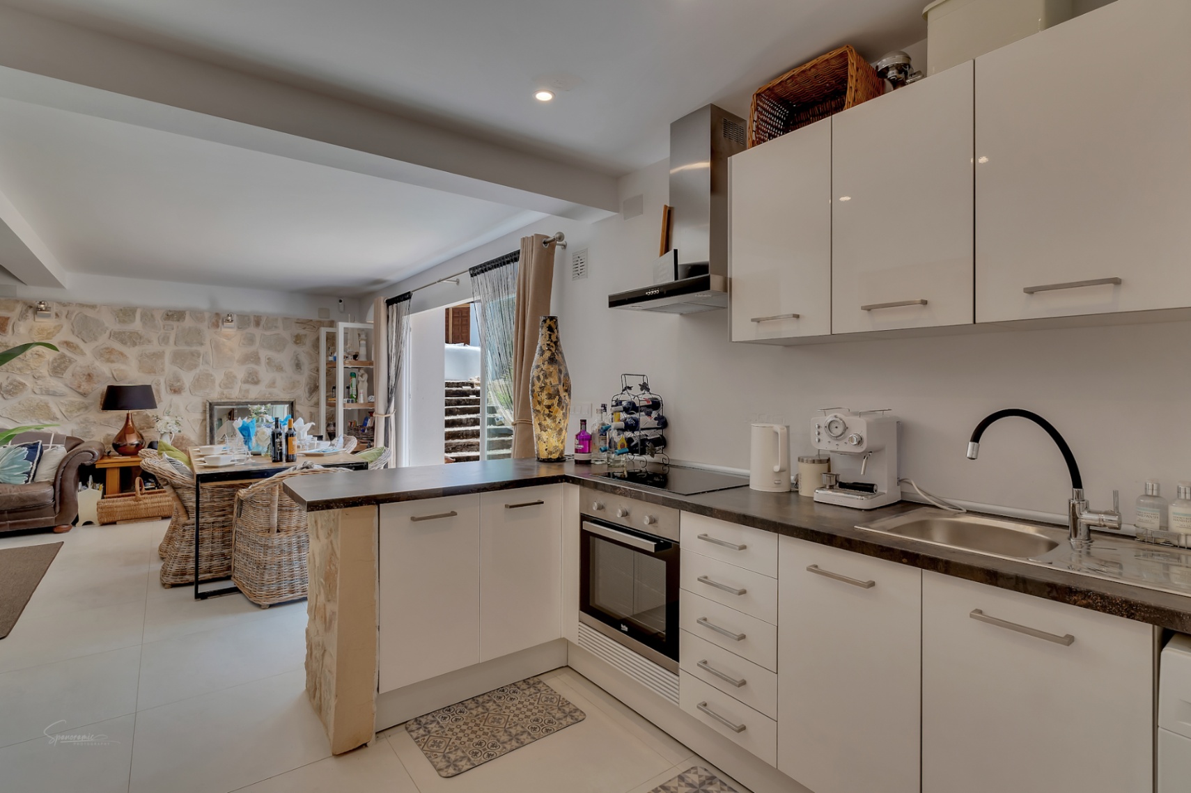 Open kitchen with dark countertops and view to dining area with stone wall.