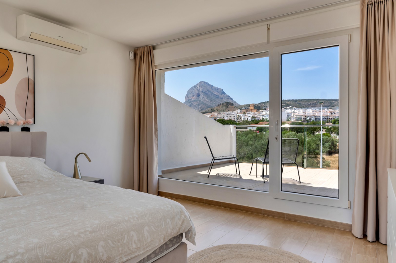 Master bedroom featuring a private terrace with panoramic views of the Montgó mountain. Includes air conditioning, tiled floors, and large glass doors.