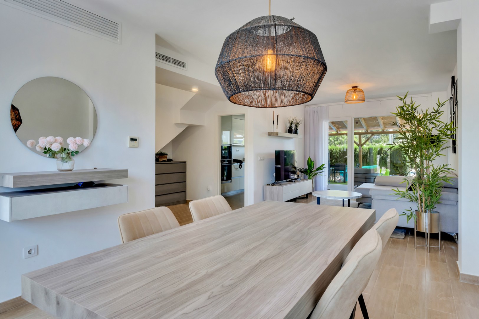 Open-concept living and dining area featuring a wooden table, designer pendant lighting, and seamless access to the private patio and garden.