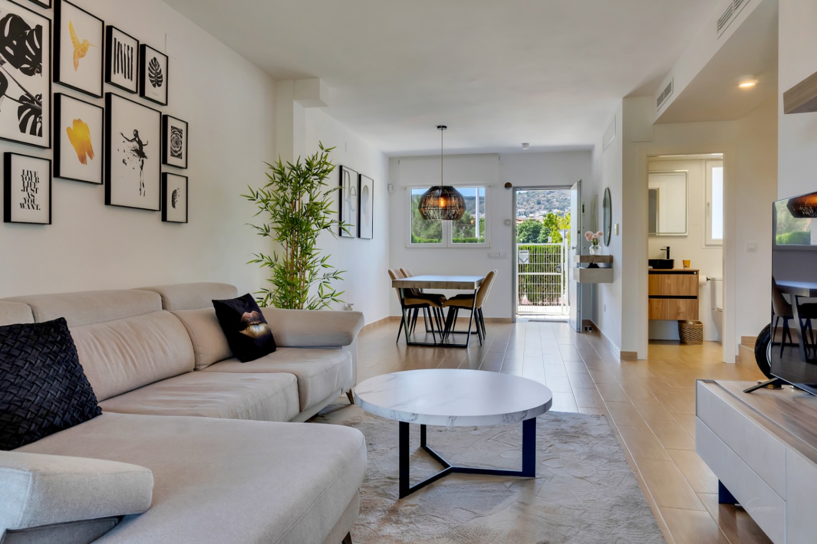 Open-concept living and dining area featuring wood-effect tile flooring, contemporary furniture, and a view towards the private patio entrance.
