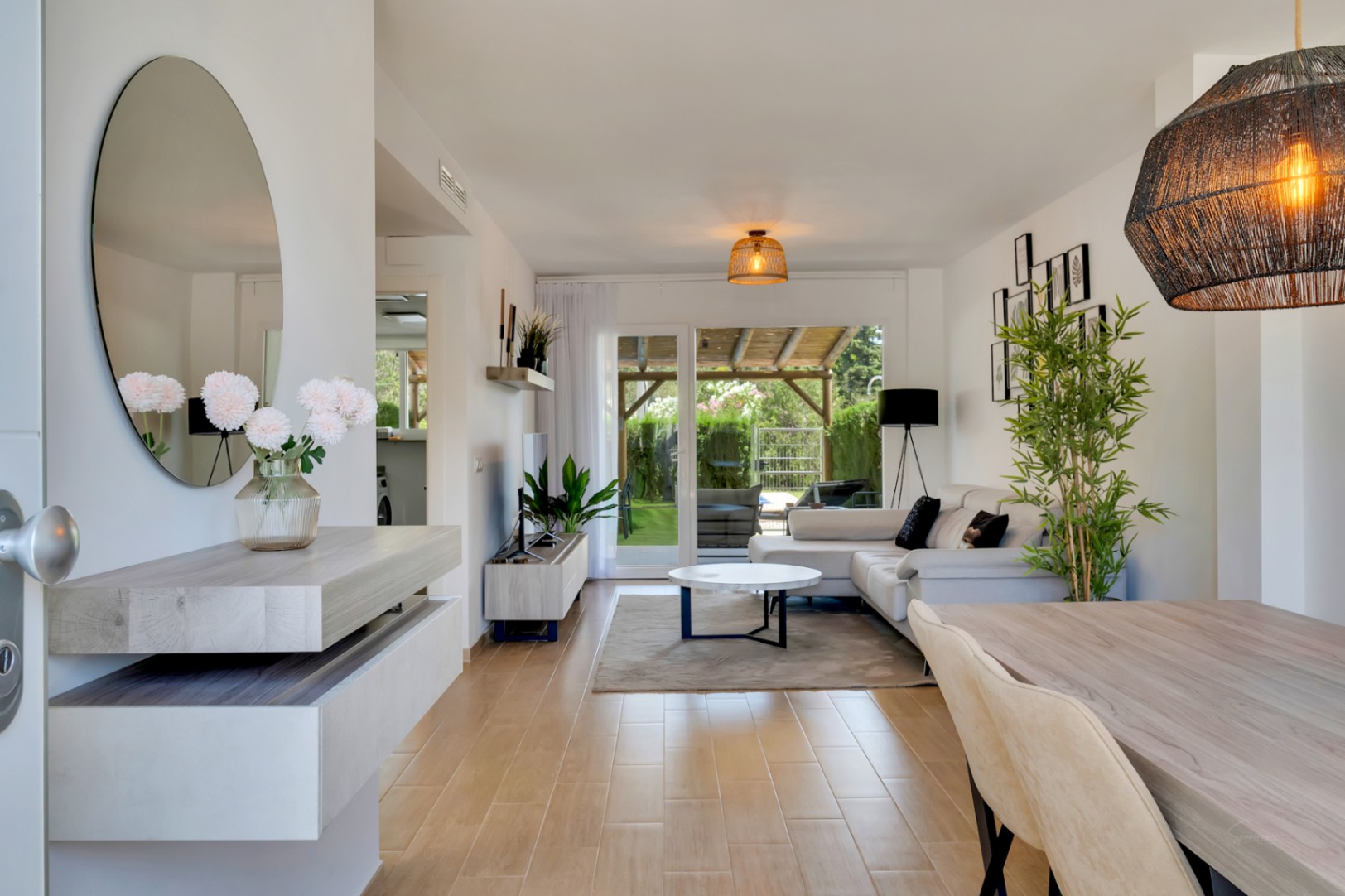 Open-plan living and dining room featuring wood-effect ceramic flooring and direct access to the private patio. Modern furnishings and natural light define the space.