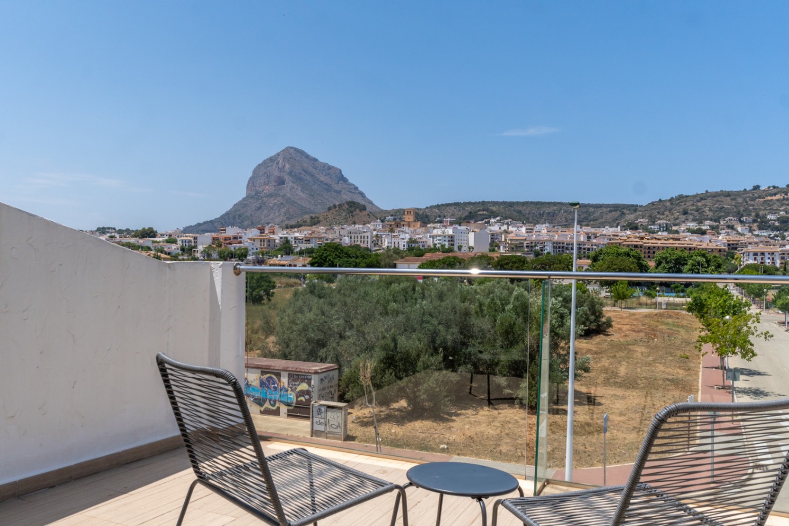 Rooftop terrace featuring a glass railing and panoramic views of the Montgó mountain and Jávea's old town. Furnished with modern seating on a durable tiled floor.