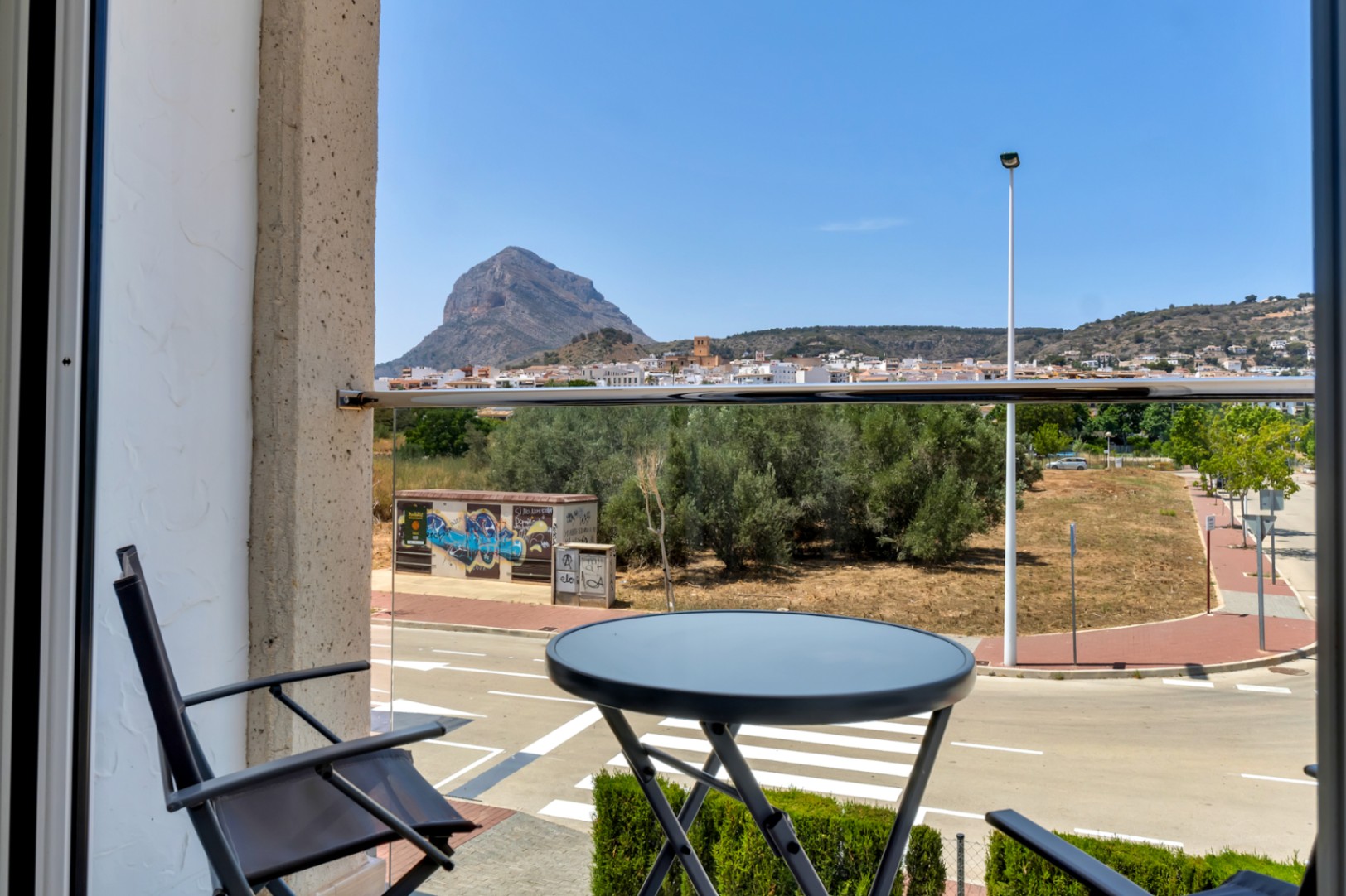 Unobstructed views of the Montgó mountain and the old town from the private balcony, featuring a modern glass railing and a compact seating area.