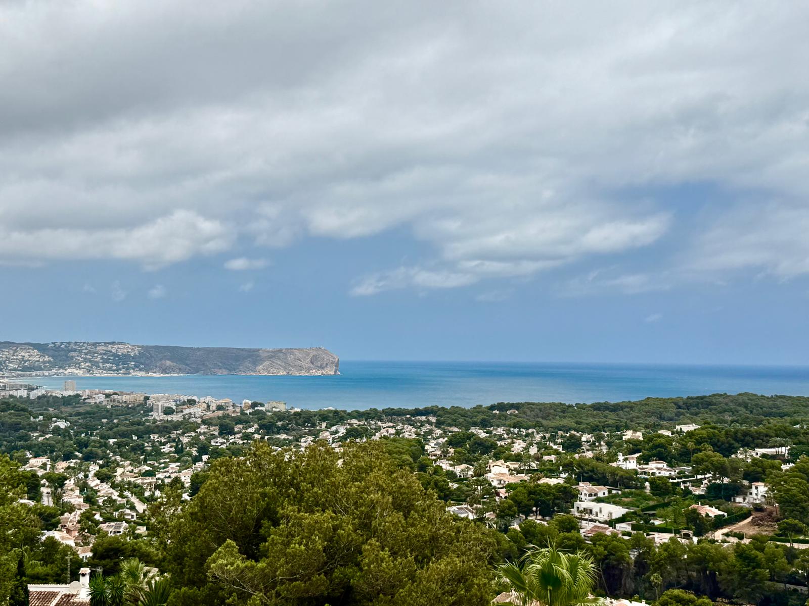 Elevated panoramic views overlooking the bay of Jávea and Cap de Sant Antoni, showcasing the Mediterranean Sea and lush residential surroundings.