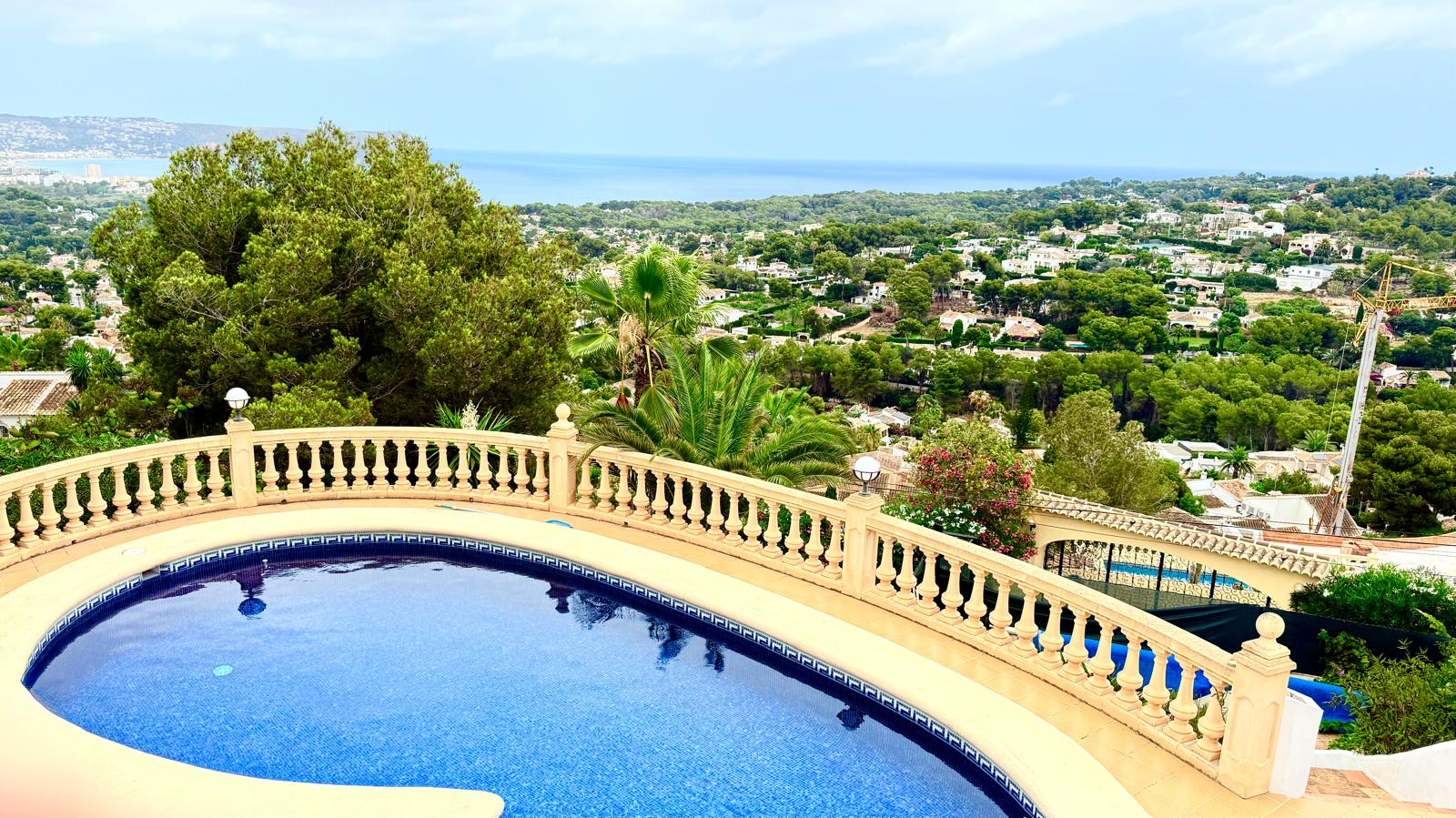 Elevated private pool with blue mosaic tiling and a classic balustrade, featuring panoramic views of the Mediterranean Sea and the lush Jávea landscape.