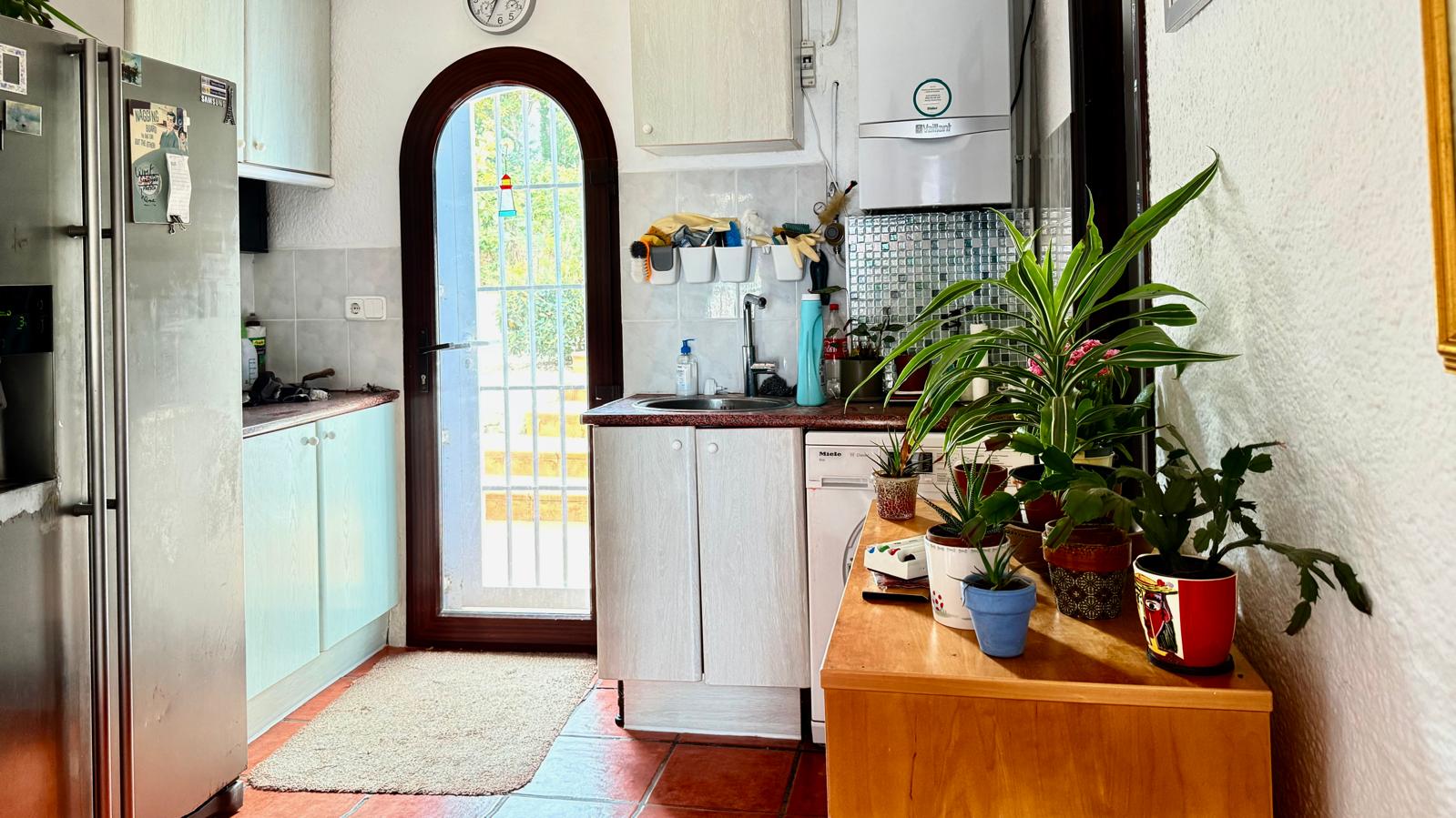 Functional kitchen featuring granite countertops, white cabinetry, and an arched glass door that provides natural light and access to the outdoor terraces.