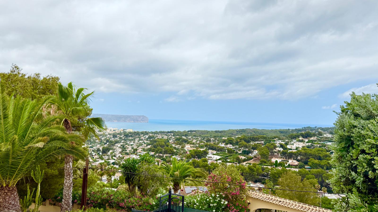 Panoramic views from the property overlooking the bay of Jávea and the Mediterranean Sea, framed by mature garden vegetation and the Cabo de San Antonio headland.