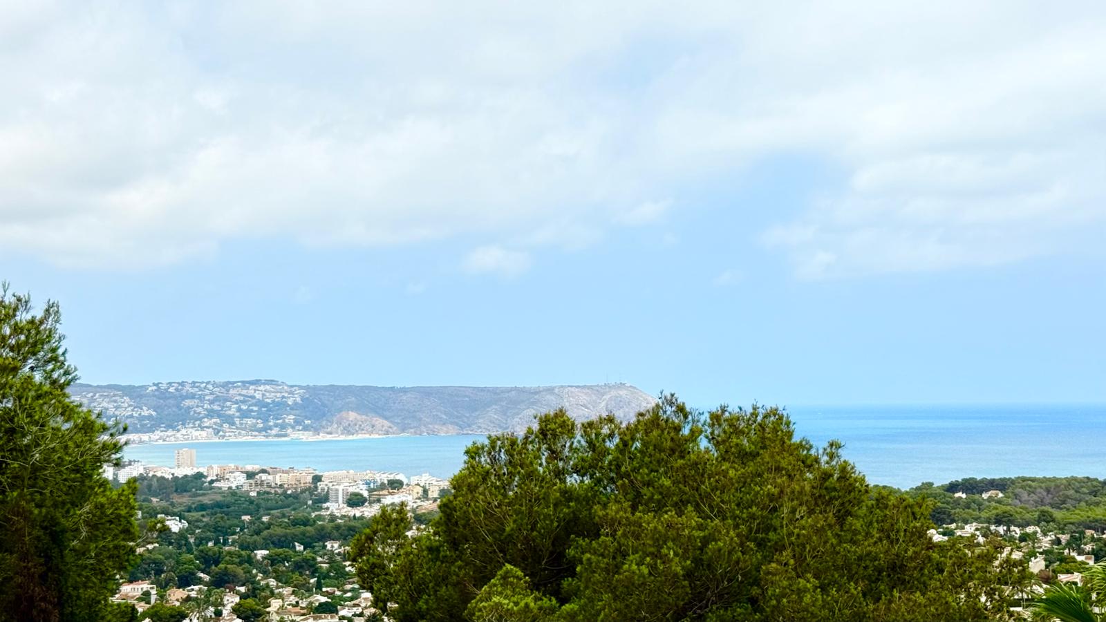 Panoramic views of Jávea bay and the Mediterranean Sea, featuring the Cap de Sant Antoni headland, framed by mature pine trees from the elevated plot.