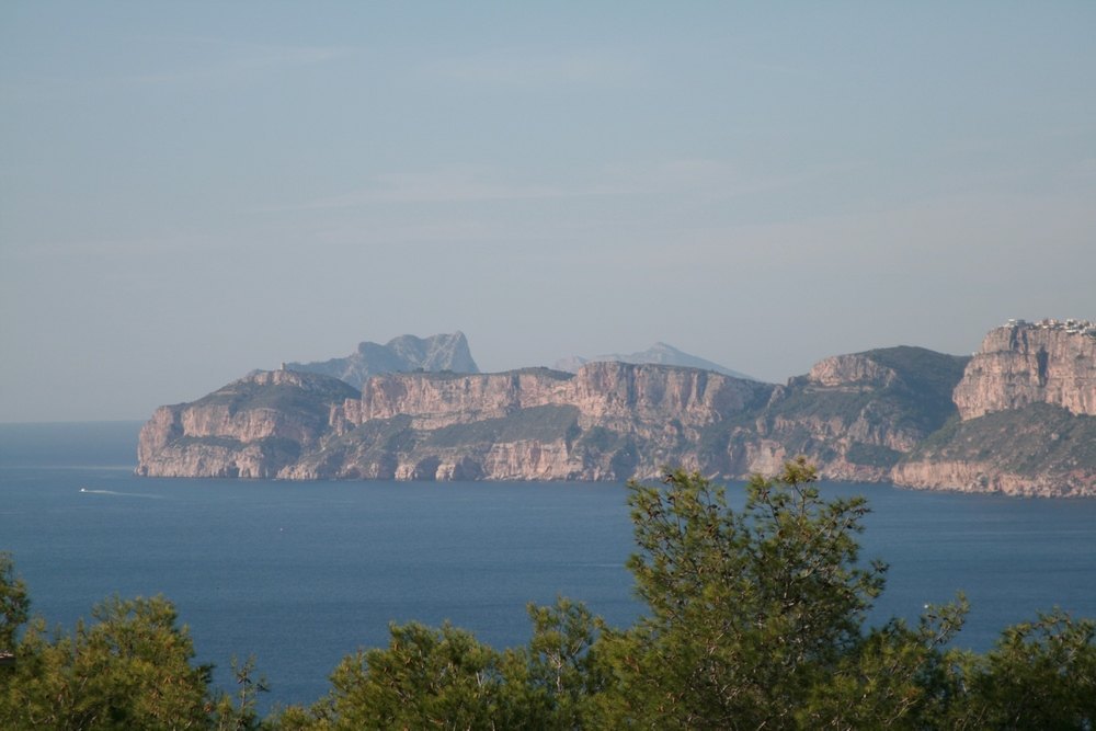 Panoramic views of the Mediterranean Sea and limestone cliffs from the plot, framed by native pine trees in the foreground.