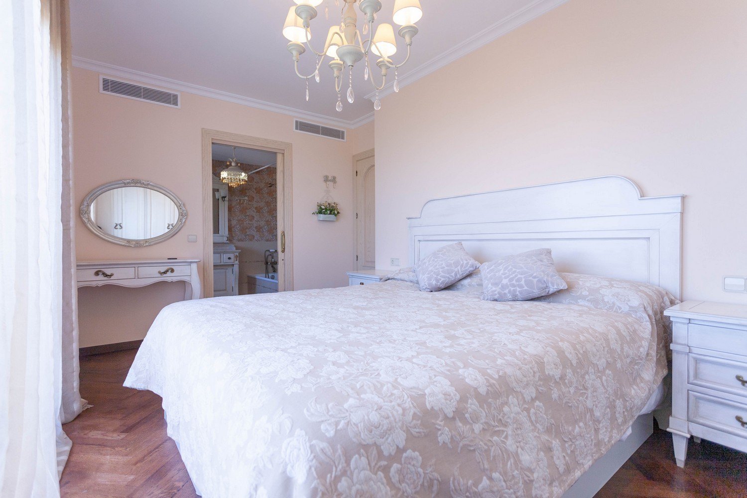 Bedroom with a double bed, vanity with oval mirror, and en-suite bathroom featuring patterned wallpaper.