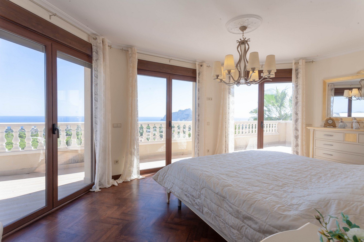Bright bedroom with sea views, balustrade balcony, and herringbone parquet flooring.