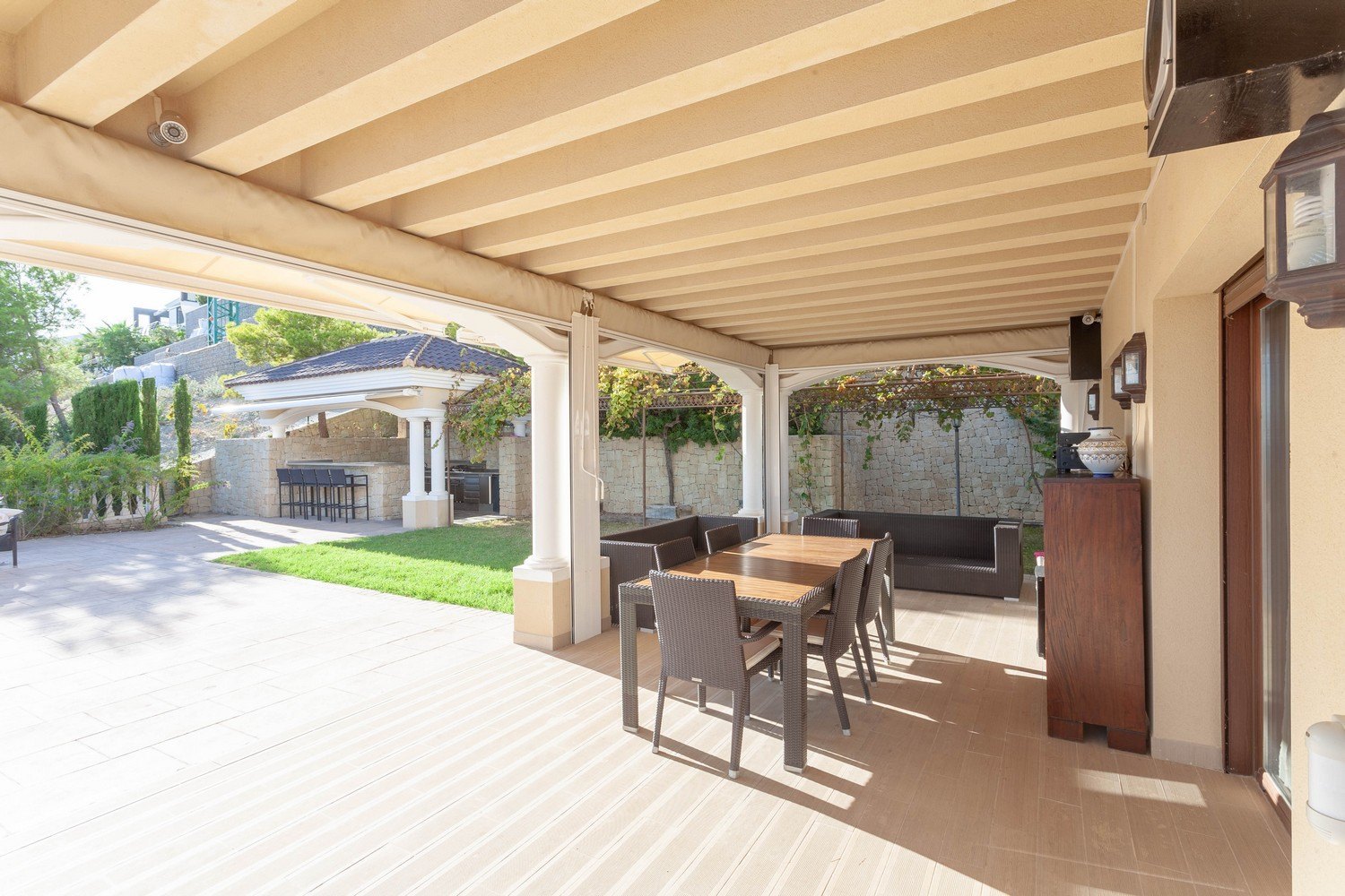 Covered terrace with dining area and garden view featuring a barbecue in Benissa, Costa Blanca.