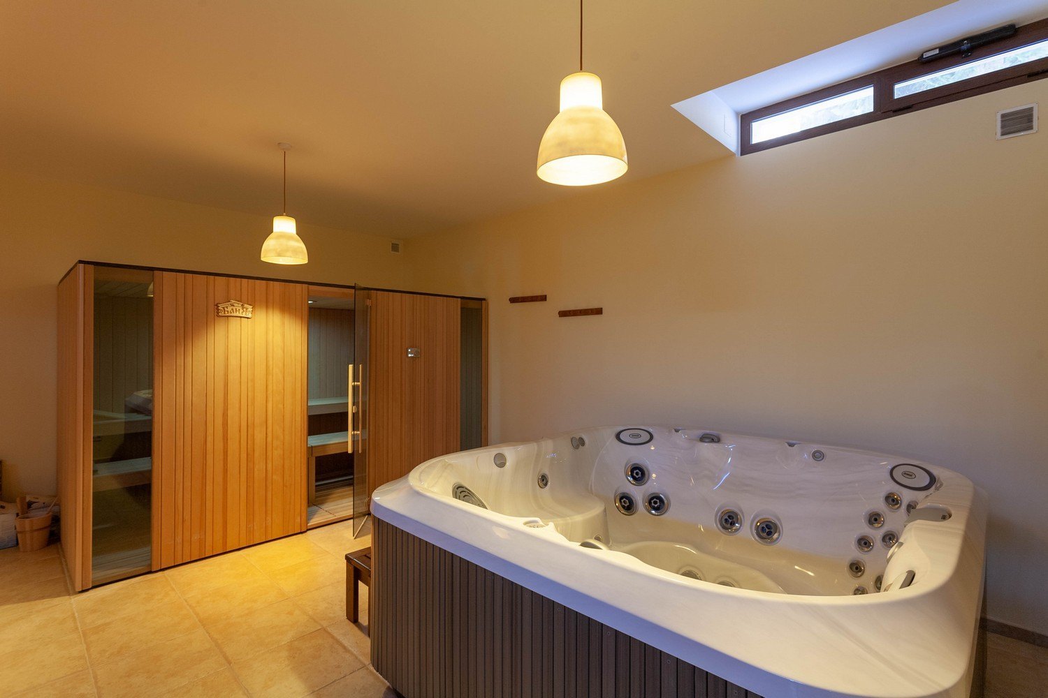 Detail of the jacuzzi and light wood sauna with glass door.