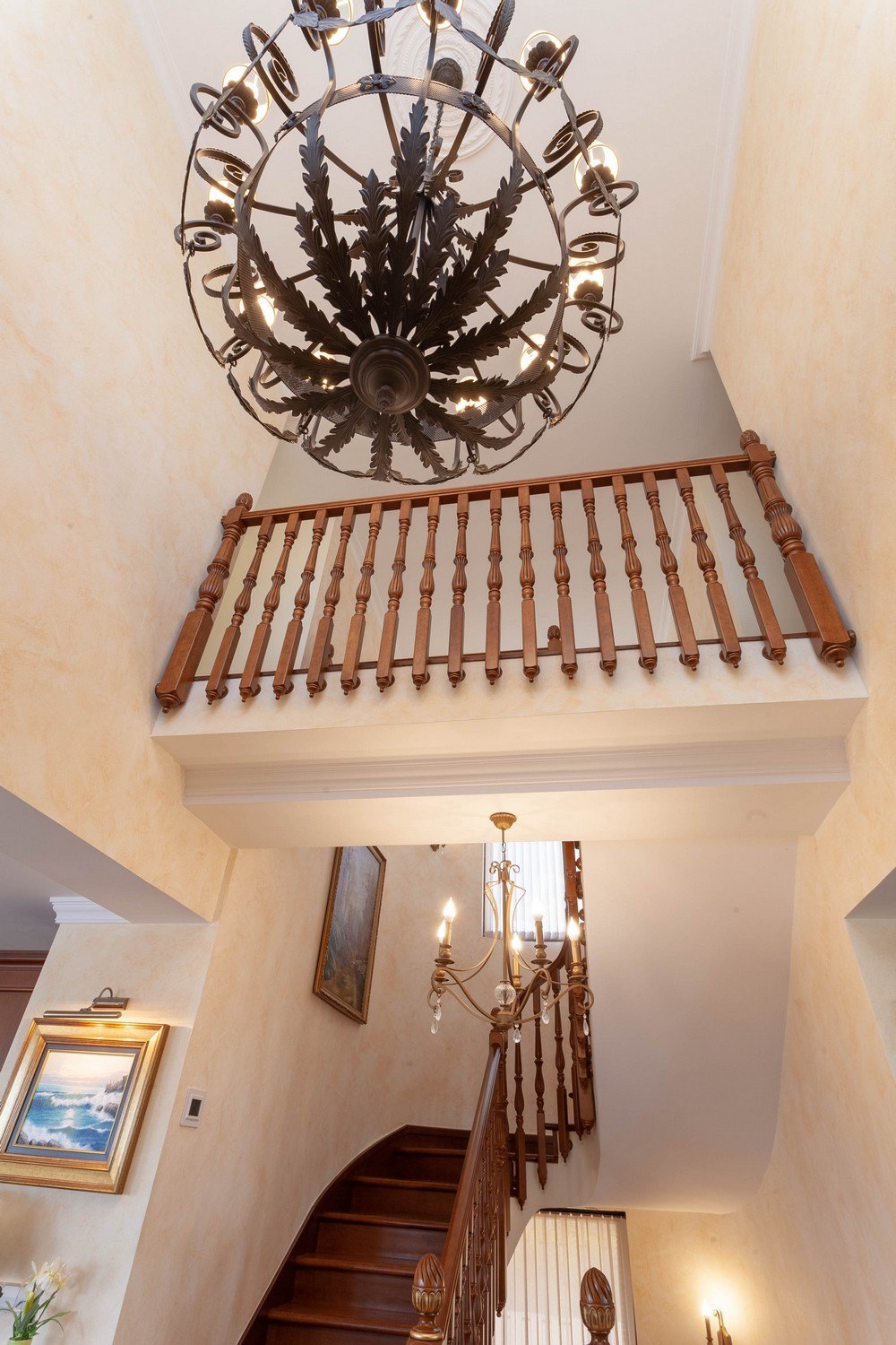 Detail of the wooden staircase with railing and decorative chandelier.