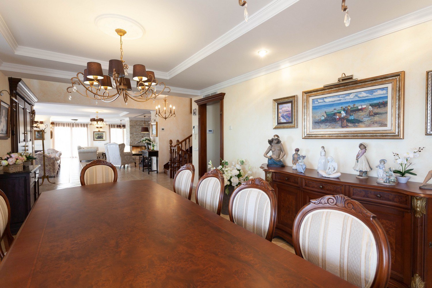 Dining room featuring a dark wood table, upholstered chairs, and a classic sideboard with decorative sculptures.