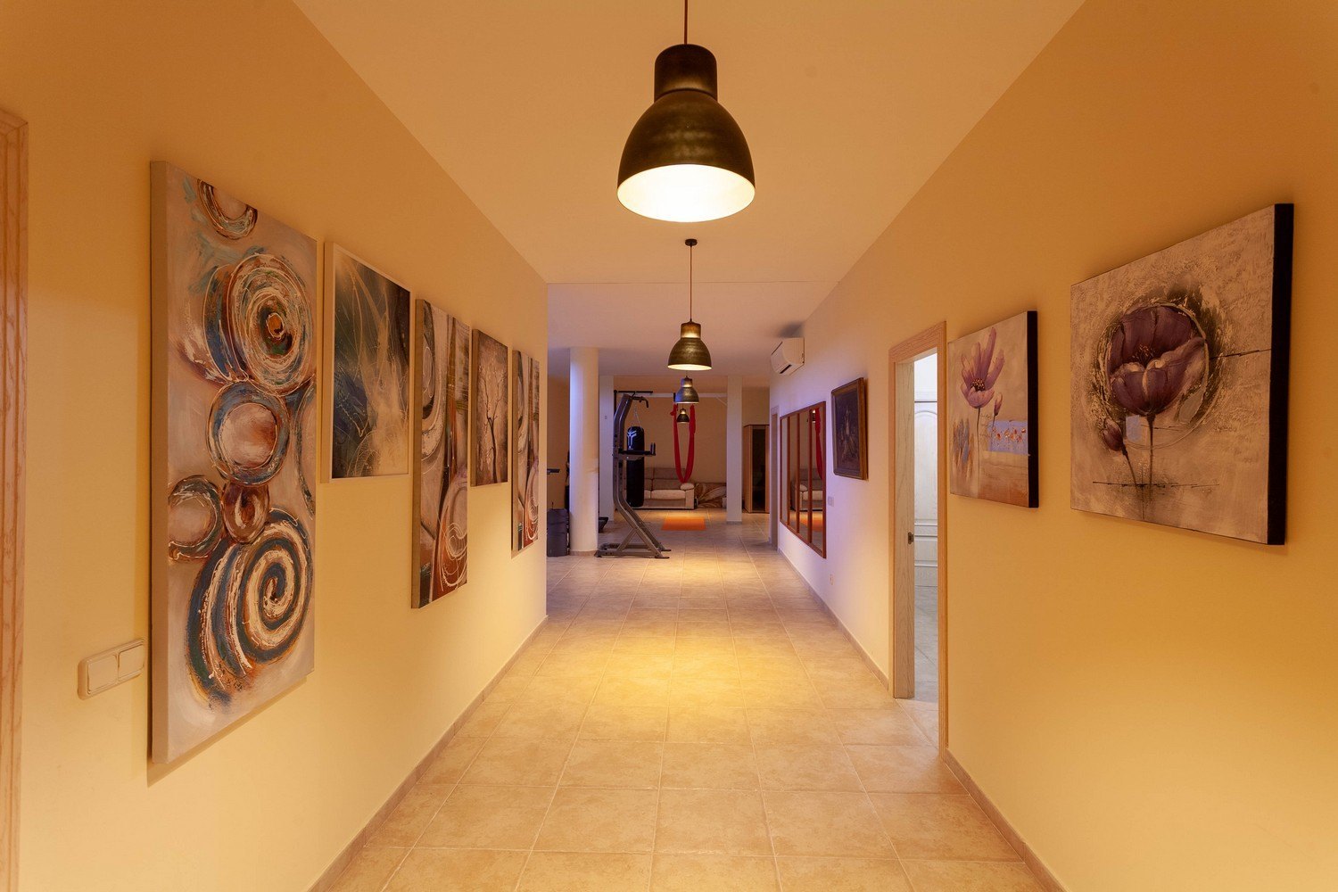 Illuminated hallway with artwork and access to the gym.