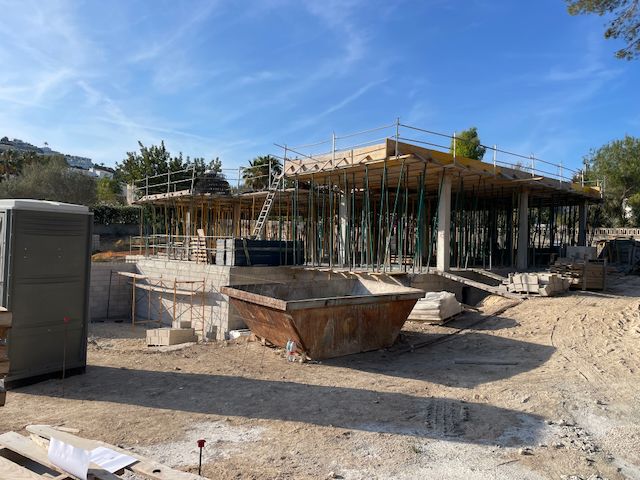 Villa under construction in Moraira. Visible are the foundation, support columns and roof formwork on a sunny day.