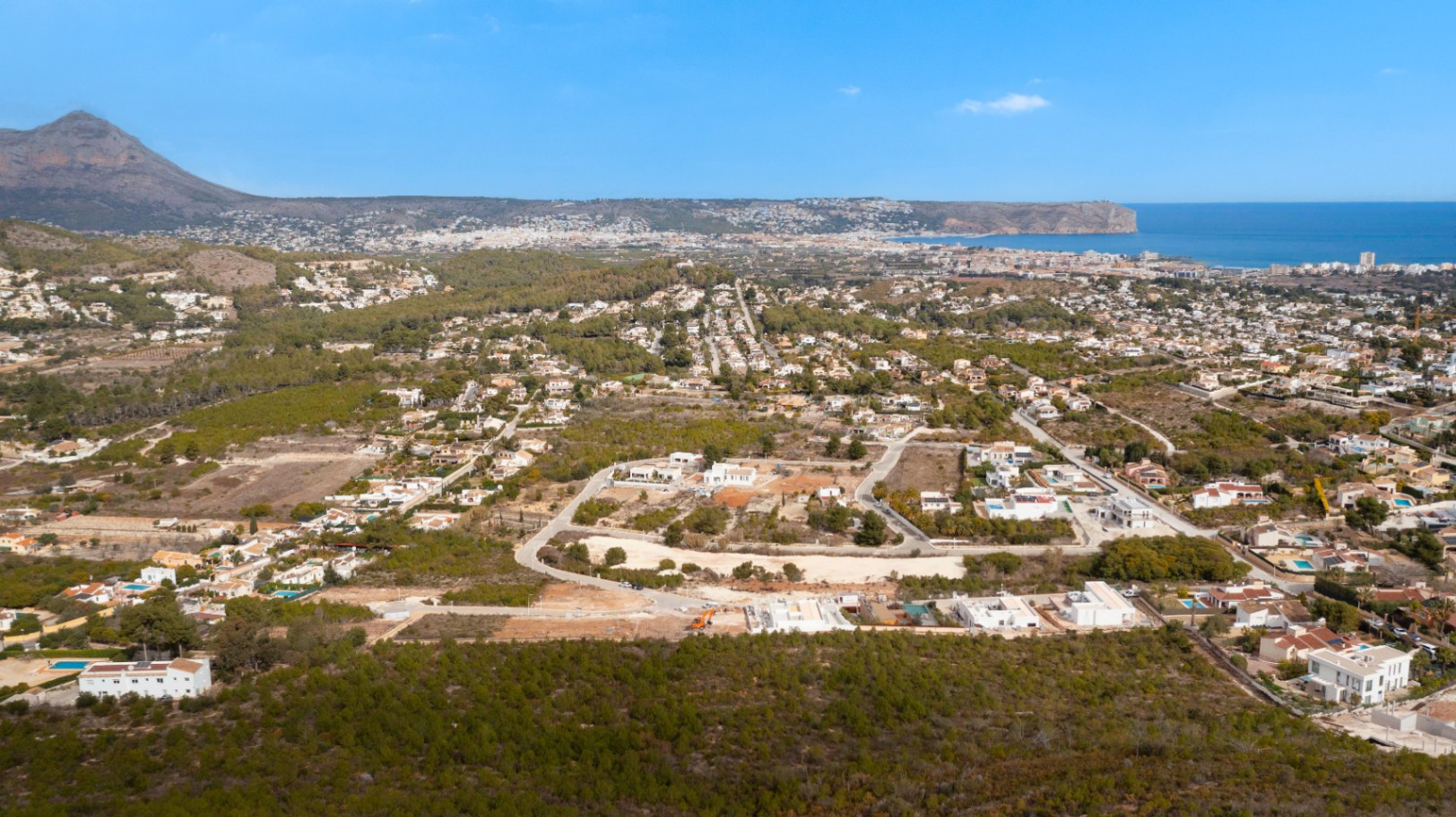 Panoramic aerial view of Lomas Del Rey in Jávea, highlighting the proximity to the Mediterranean Sea and the Montgó mountain within a residential setting.