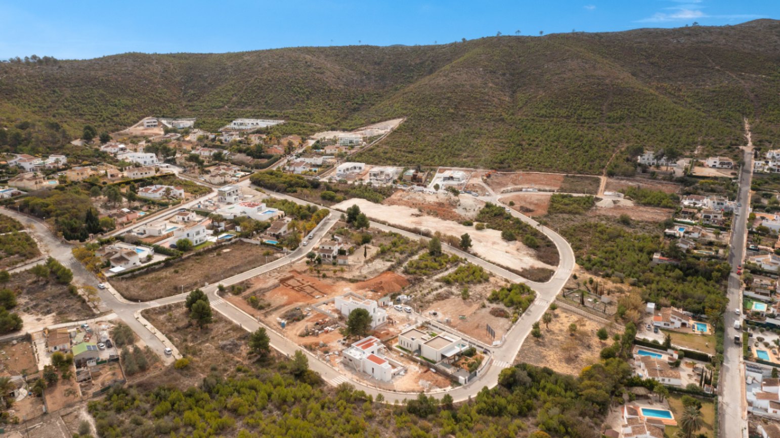 Aerial view of the Lomas Del Rey residential area in Jávea, featuring available plots and the integration of villas within the Mediterranean hillside landscape.