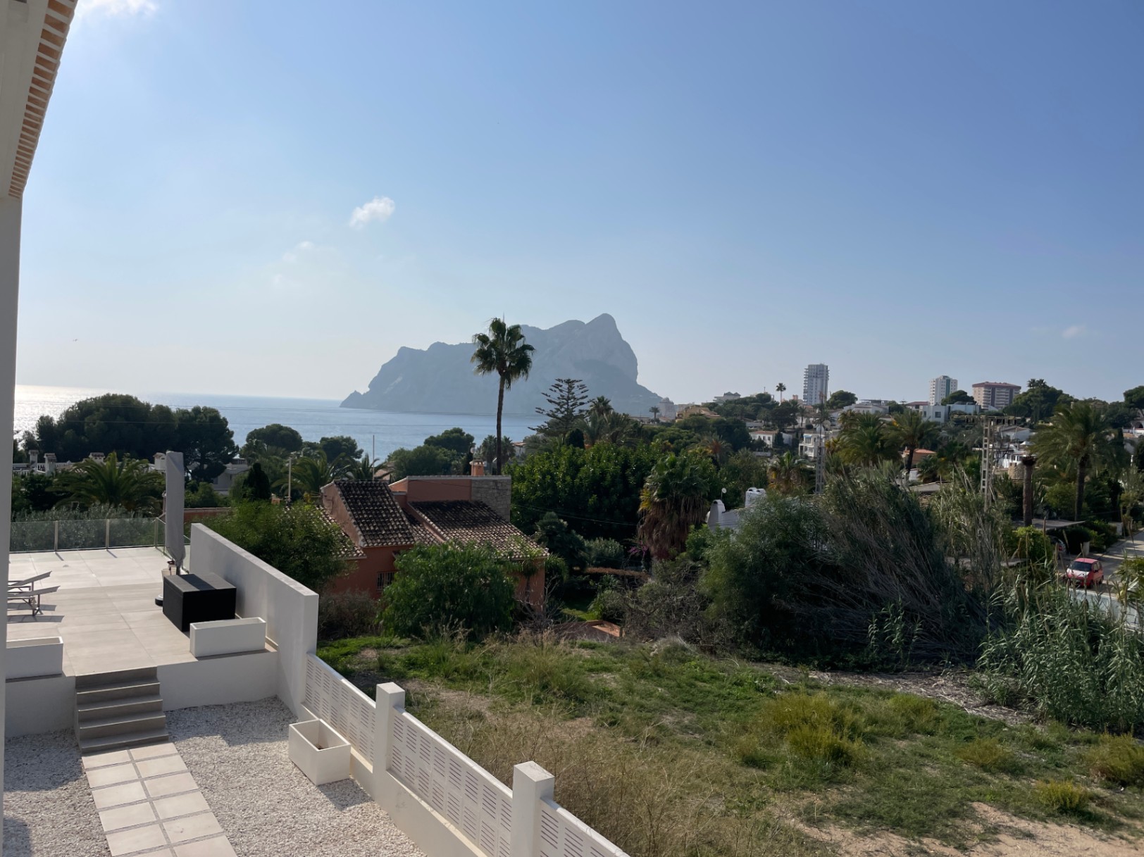 Panoramic views of the Peñón de Ifach and the Mediterranean Sea from a modern tiled terrace surrounded by lush greenery in Bassetes, Calpe.