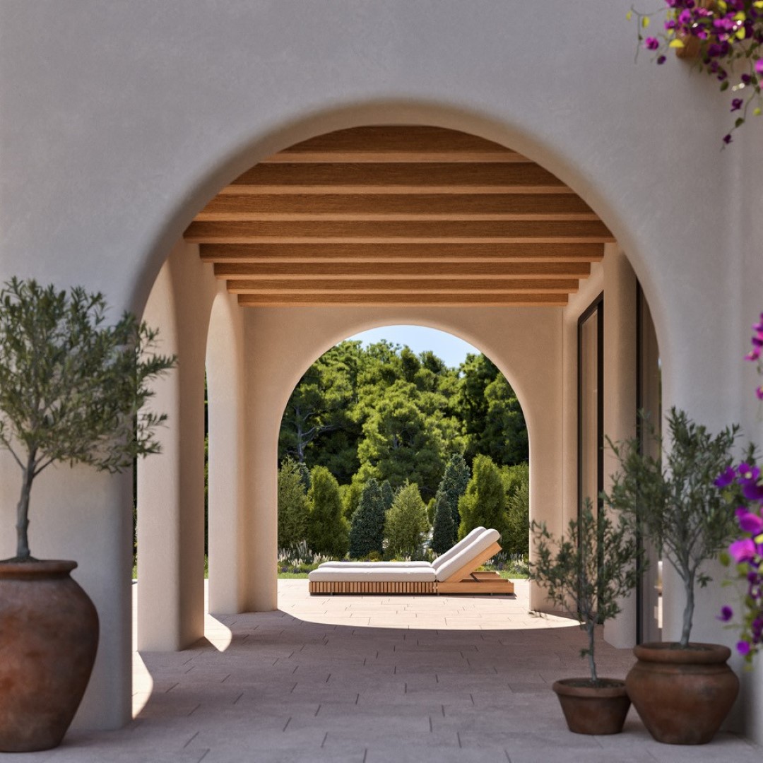 Mediterranean-style naya featuring elegant arches, wooden beam ceilings, and stone flooring. The shaded terrace opens to a garden with sun loungers and olive trees.