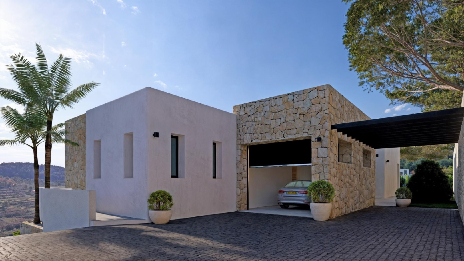 Modern exterior with stone-clad garage and gray paved driveway.