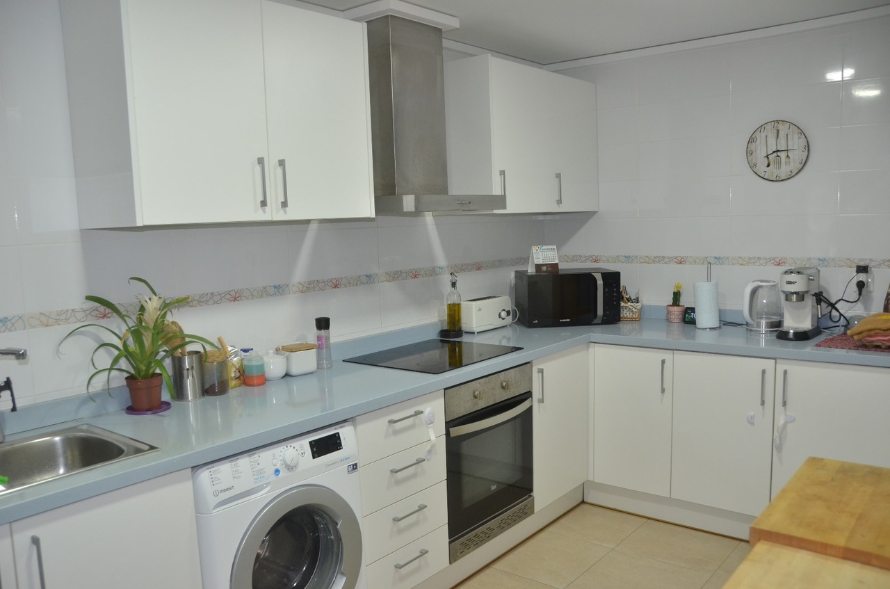 Kitchen featuring white cabinetry, a light blue countertop, and integrated appliances such as a washing machine, oven, and ceramic hob.