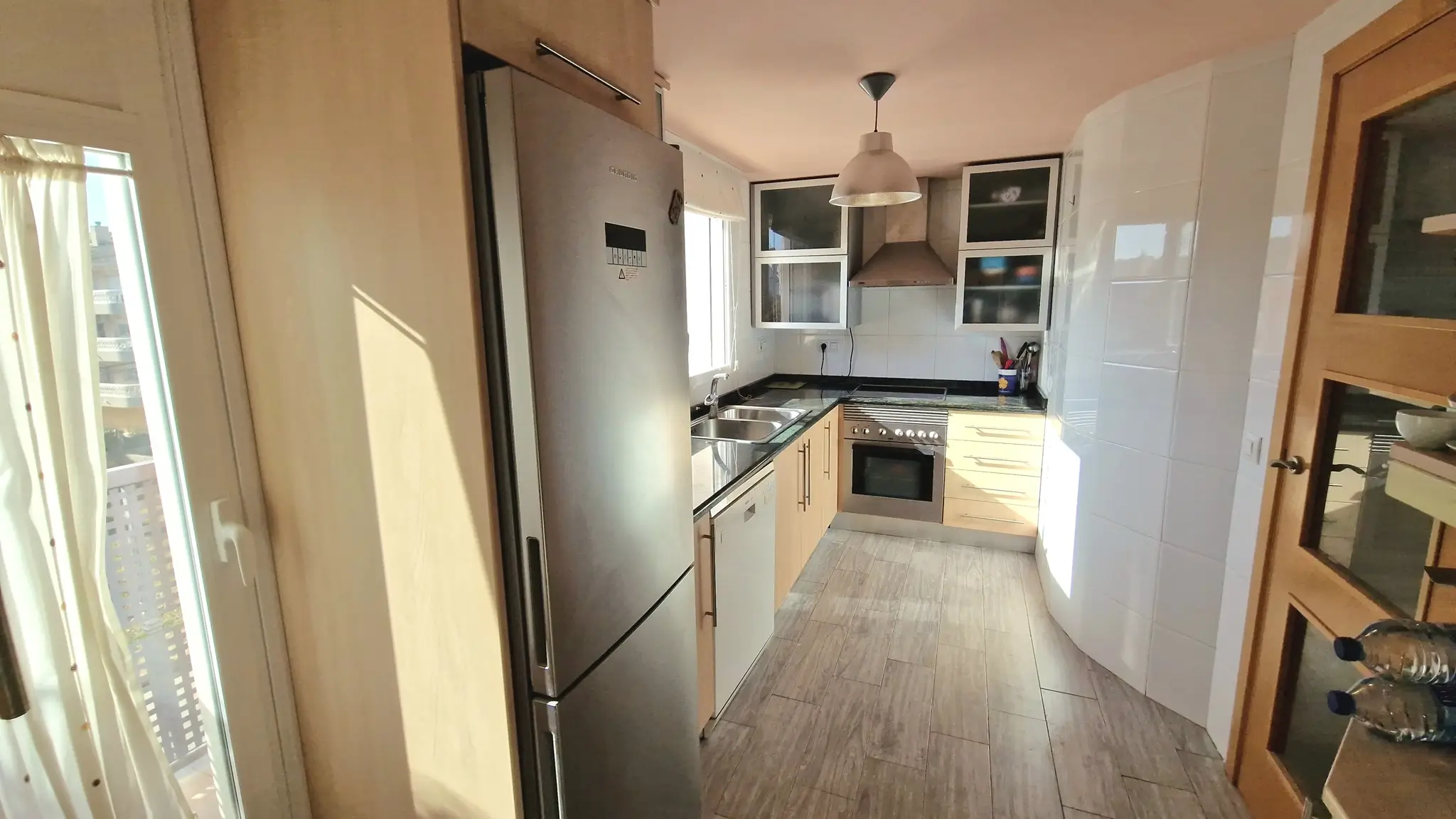 Kitchen featuring light wood cabinetry, black granite countertops, and stainless steel appliances. Includes wood-effect tile flooring and access to natural light.