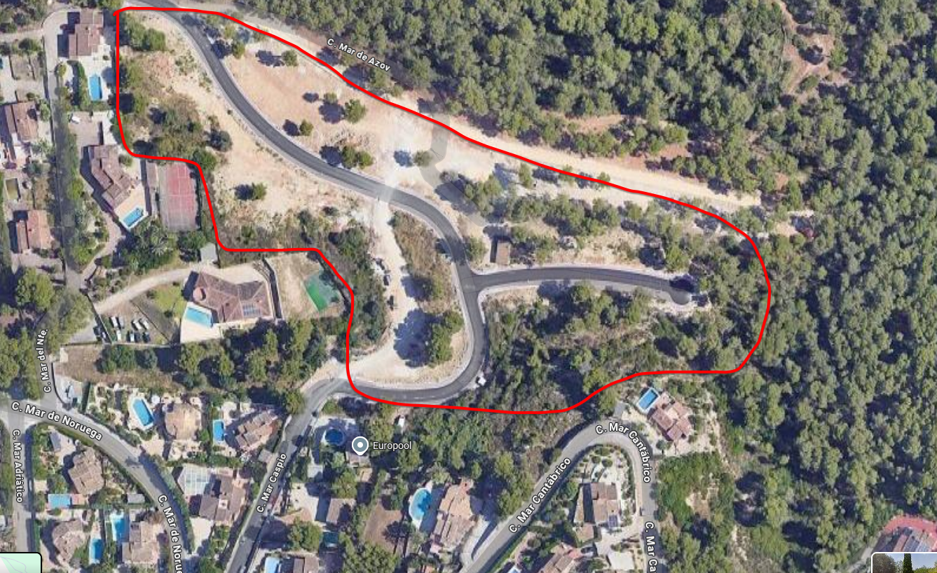 Aerial view of a residential development plot outlined in red, featuring paved access roads and Mediterranean vegetation near existing villas with pools.