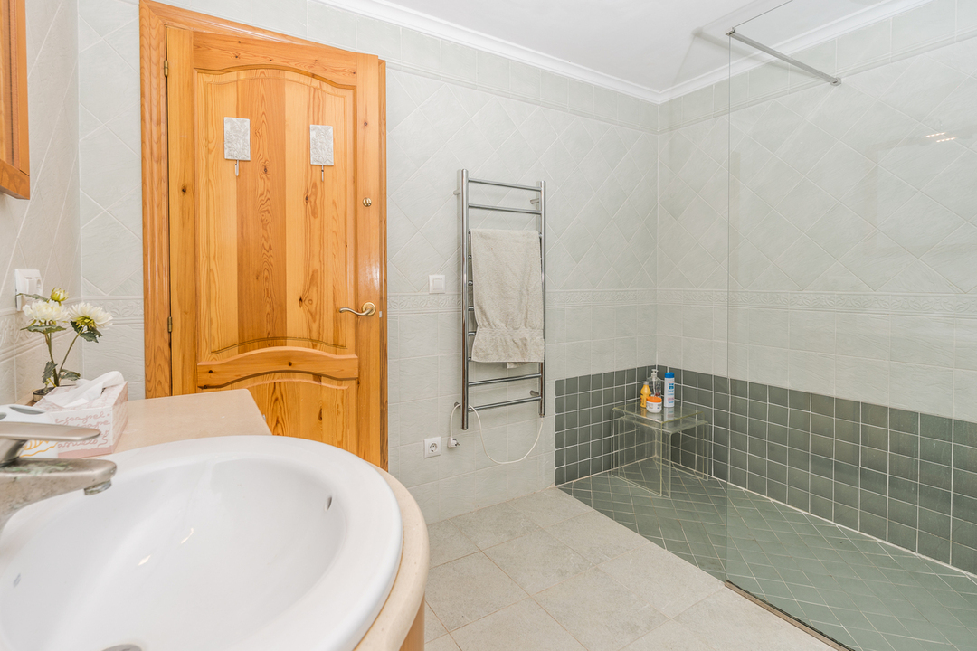 Bathroom featuring a walk-in shower with green tiling, a glass screen, and a chrome heated towel rail next to a solid wood door.