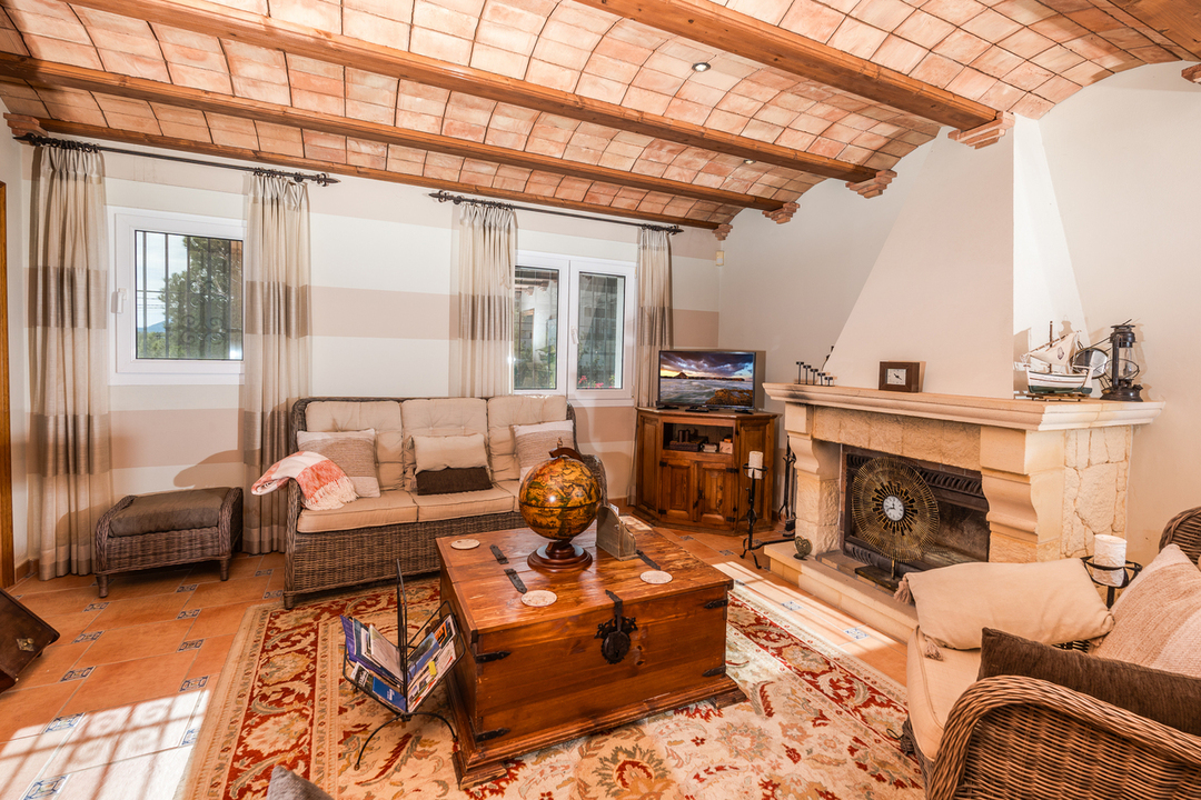 Living room featuring a traditional Catalan vaulted ceiling with wooden beams, a stone fireplace, and rustic terracotta tile flooring.