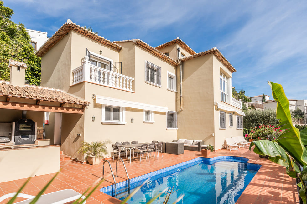 Mediterranean villa exterior featuring a private swimming pool, terracotta tiled terrace, outdoor dining set, and a built-in summer kitchen.