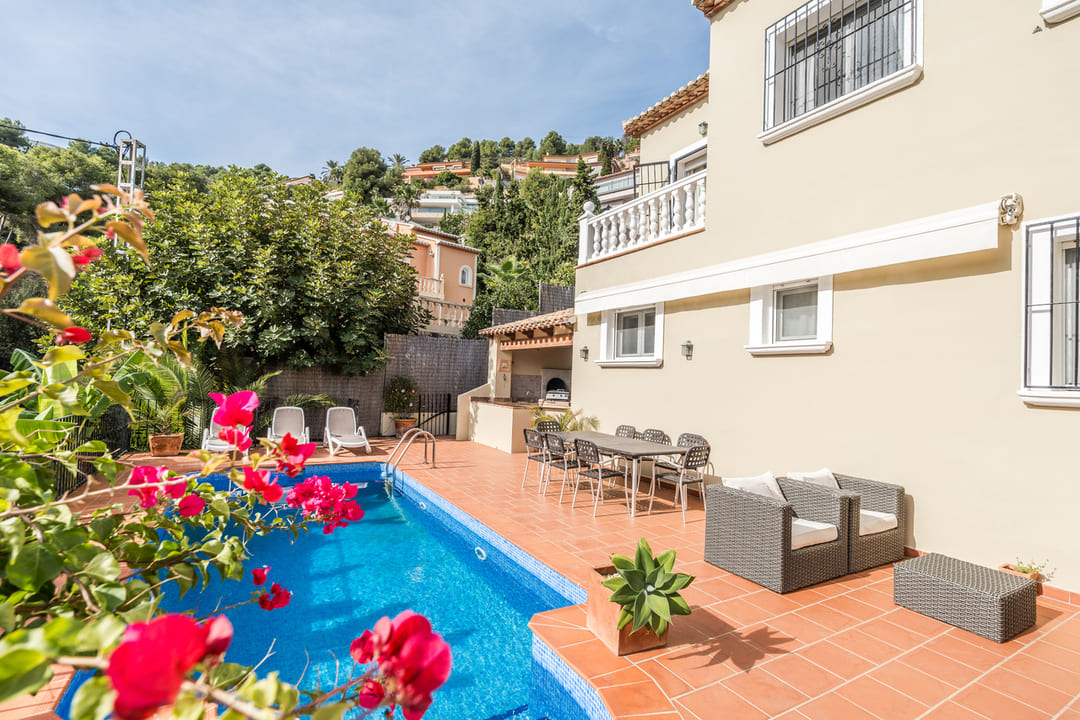 Terrace with a private swimming pool, terracotta tiling, and an outdoor dining area. Features a built-in barbecue and lounge furniture against a cream facade.