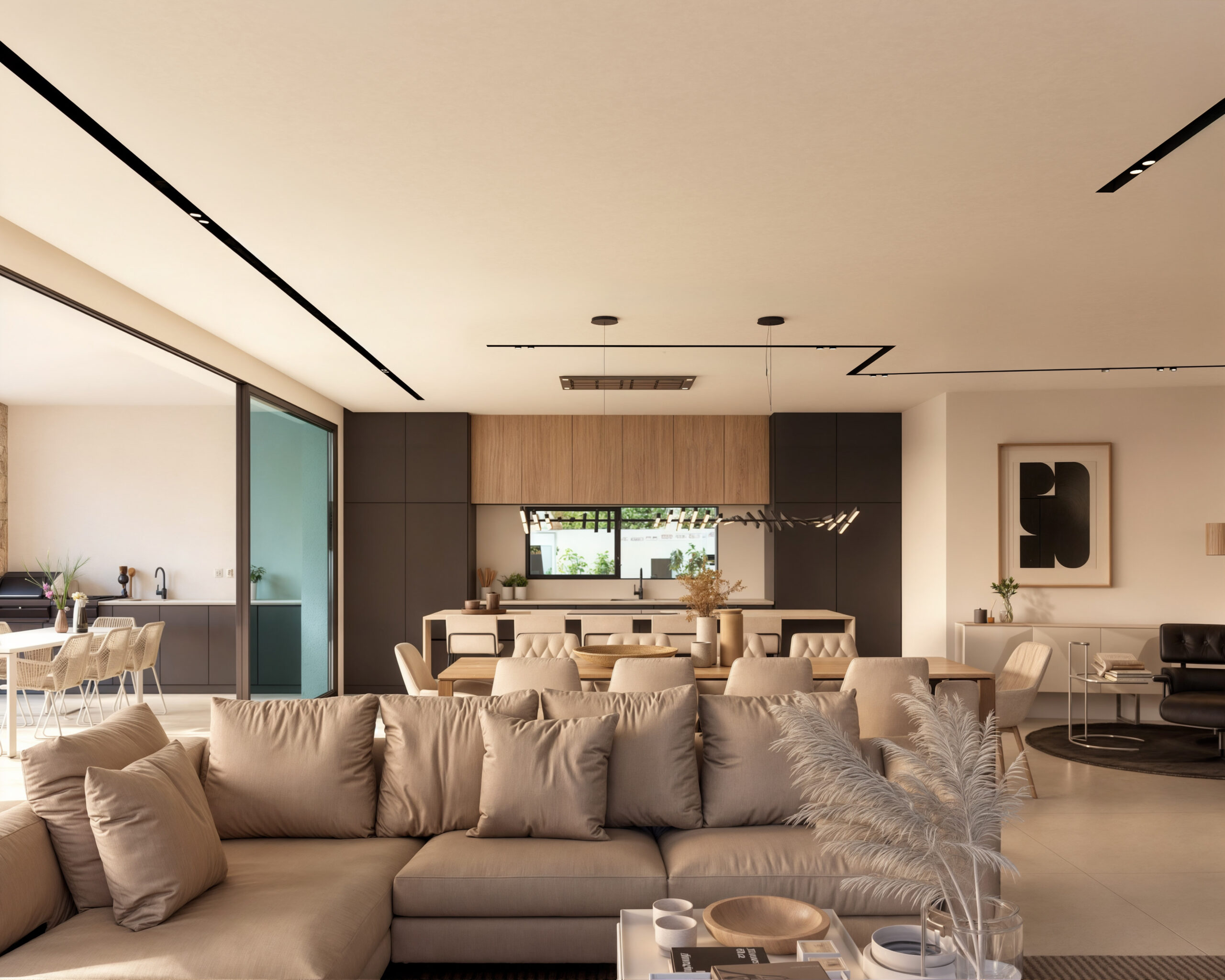 Open-plan living space featuring a large beige sectional sofa, a wooden dining set, and a modern kitchen with dark cabinetry and integrated track lighting.
