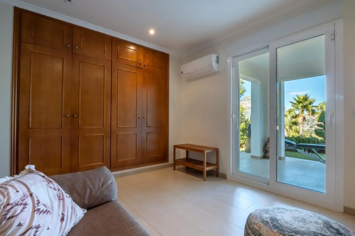 Bedroom featuring a large built-in wooden wardrobe, wall-mounted air conditioning, and sliding glass doors leading to a terrace with garden views.
