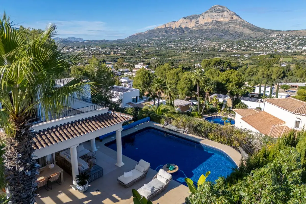 Elevated view of the private pool and covered terrace with white columns, featuring panoramic views of the valley and the Montgó mountain range.
