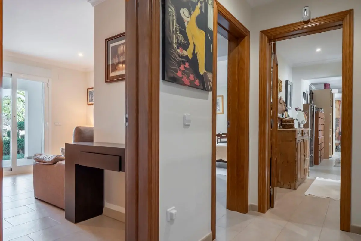 Hallway featuring wooden door frames, light tiled flooring, and views into the living area and adjacent rooms with classic wooden furniture.