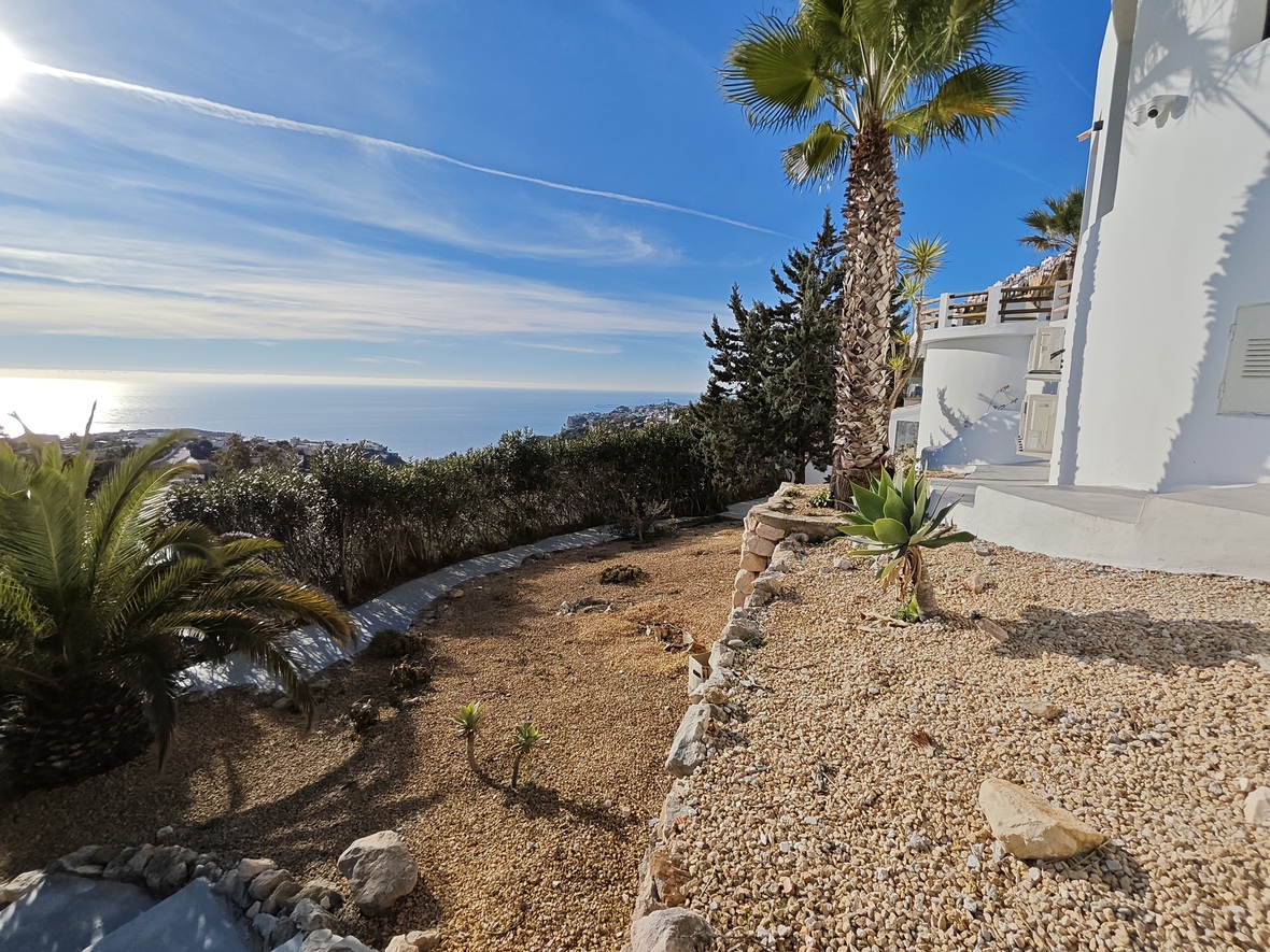 Elevated garden terrace with gravel landscaping, featuring native succulents and palm trees overlooking the Mediterranean coastline and open sea.
