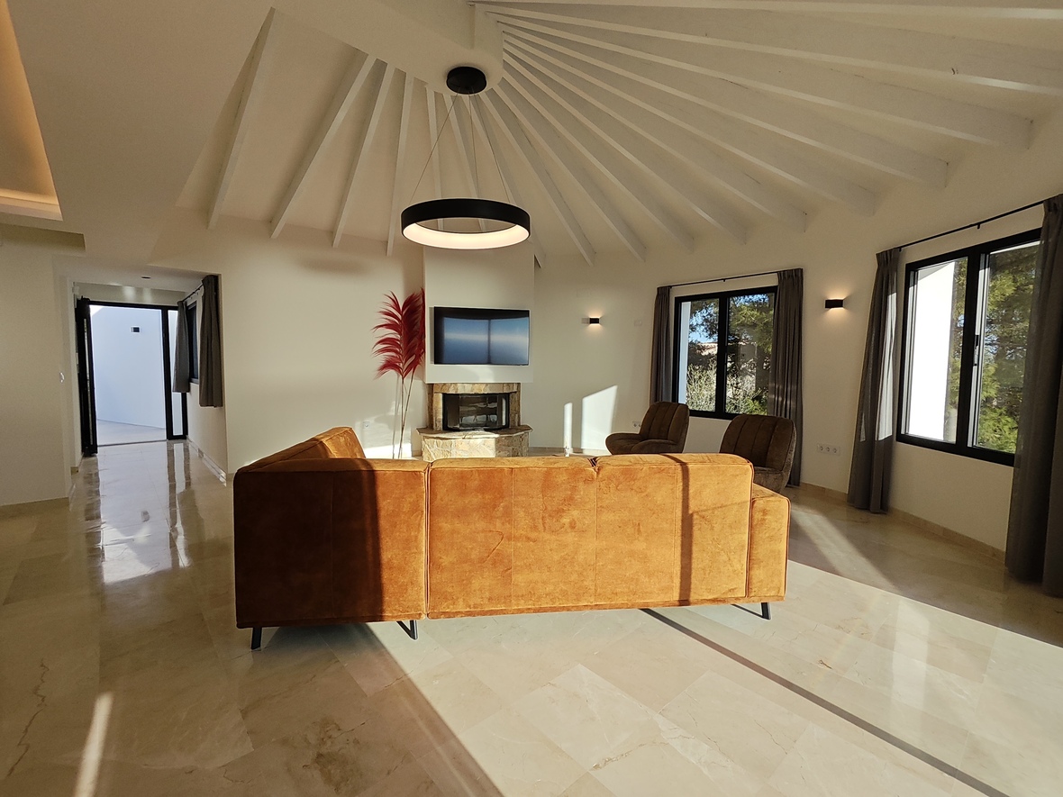 Spacious living area featuring a vaulted ceiling with white radial beams, a circular pendant light, and a stone fireplace integrated with a media wall.