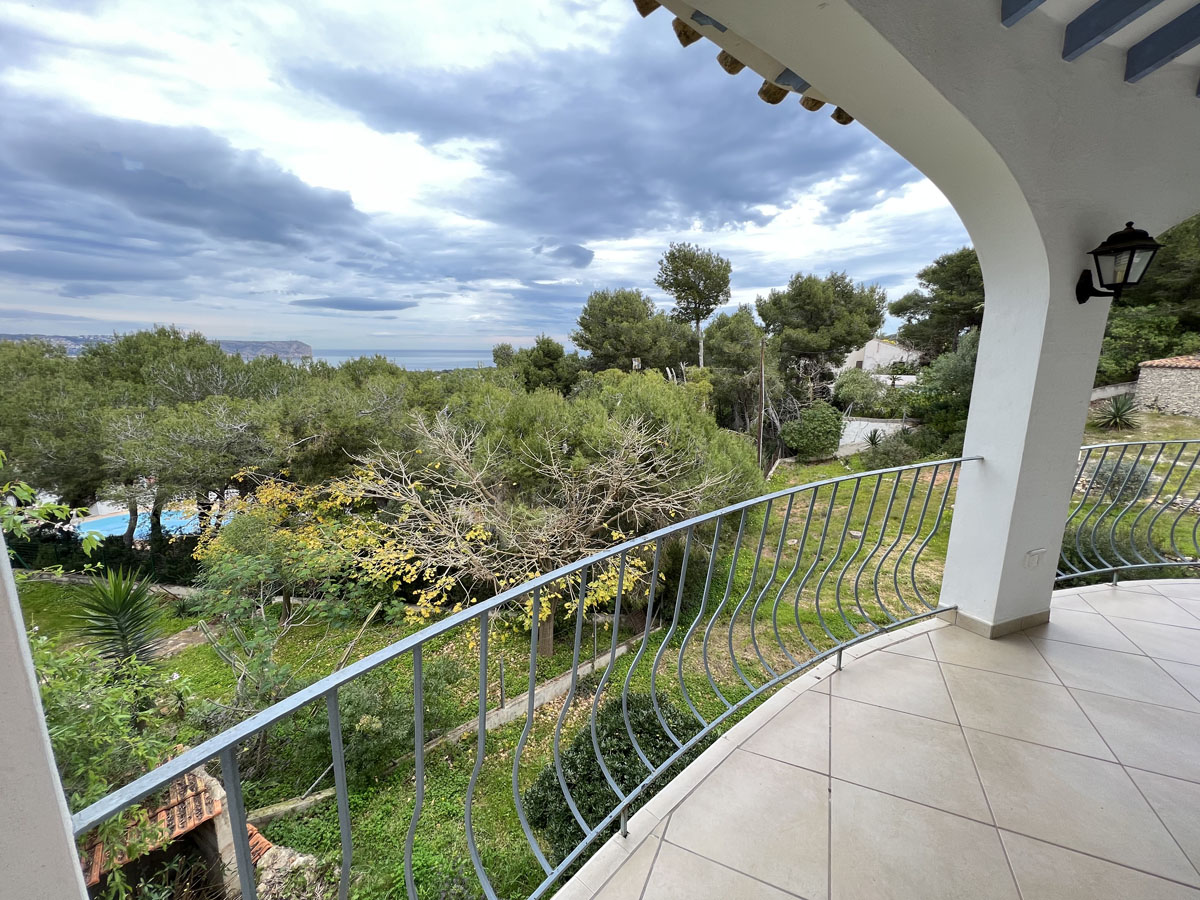 Covered terrace with tiled flooring and curved metal railings, featuring elevated views of the Mediterranean Sea and Cabo San Antonio coastline.