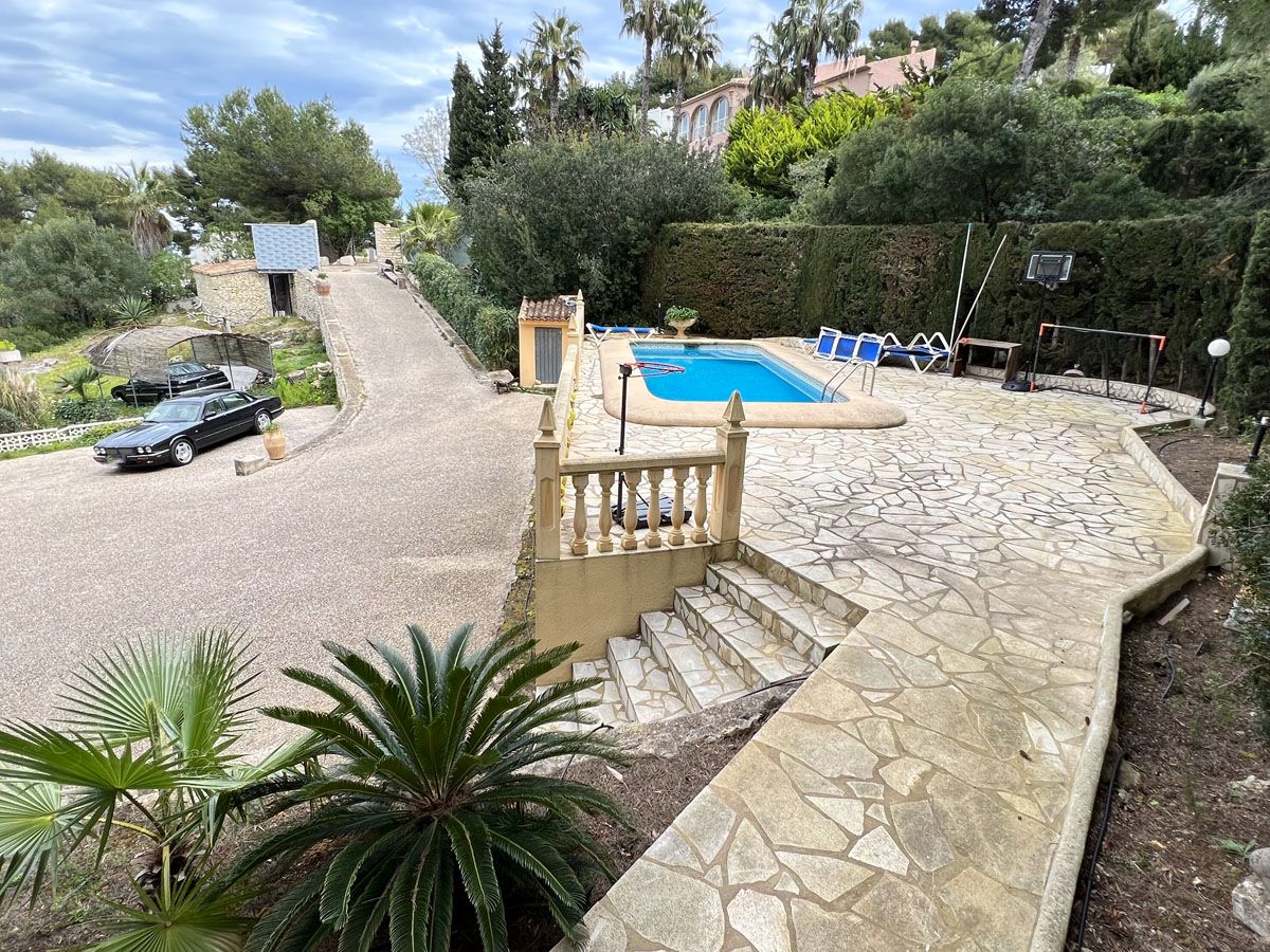 Elevated terrace featuring an 8x4 meter swimming pool with natural stone paving, overlooking the private driveway and surrounded by mature Mediterranean gardens.