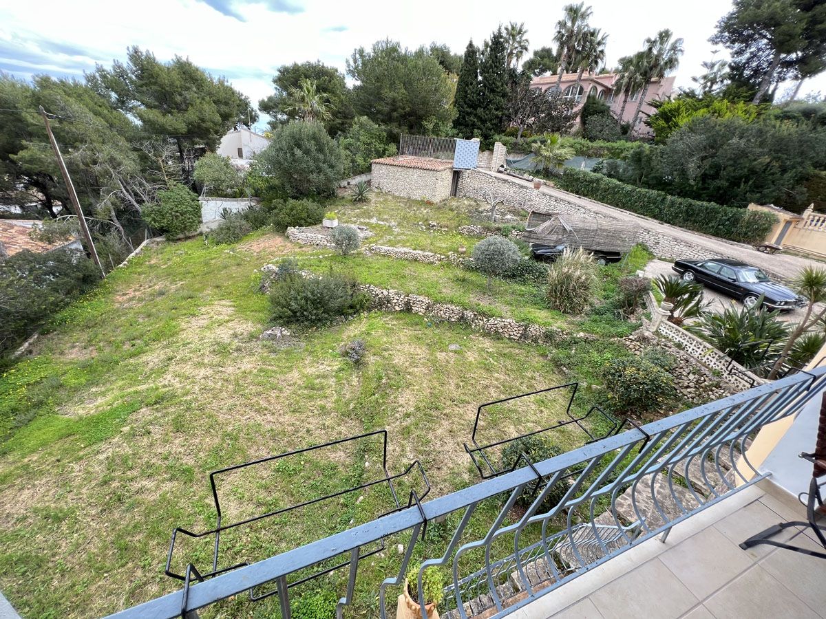 Elevated view from the terrace overlooking the terraced garden plot with traditional stone walls and mature Mediterranean trees.