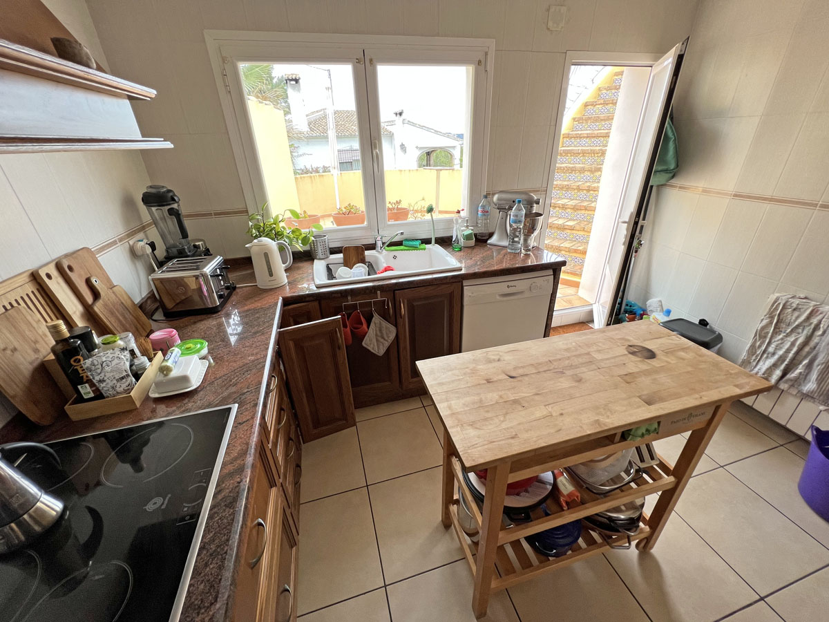 Separate kitchen featuring granite countertops, wooden cabinetry, and a central butcher block island. A door opens to an outdoor staircase with decorative tiling.