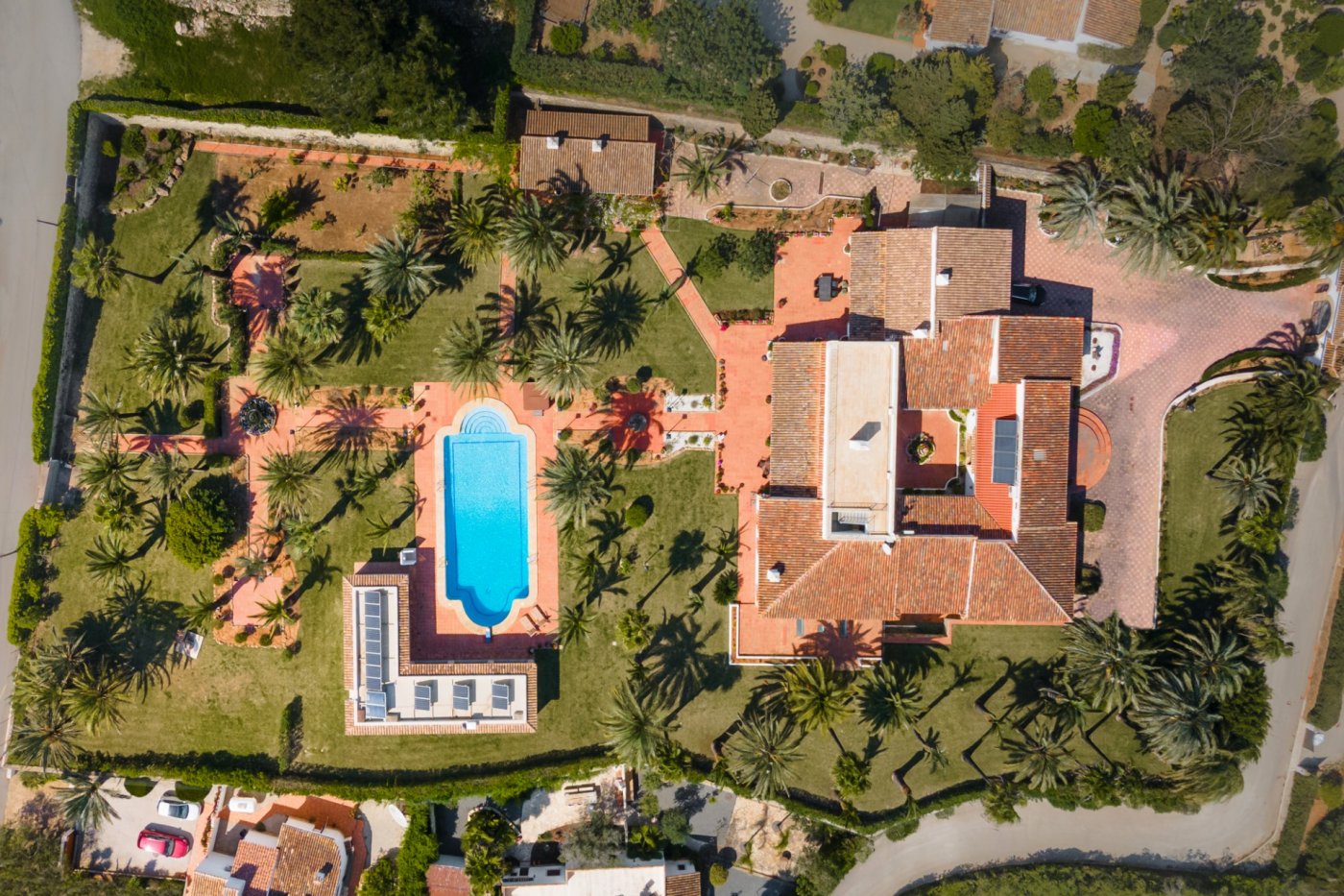 Aerial view of the estate showcasing the main villa with its central courtyard, the 16x7m swimming pool, and the extensive palm-filled grounds.