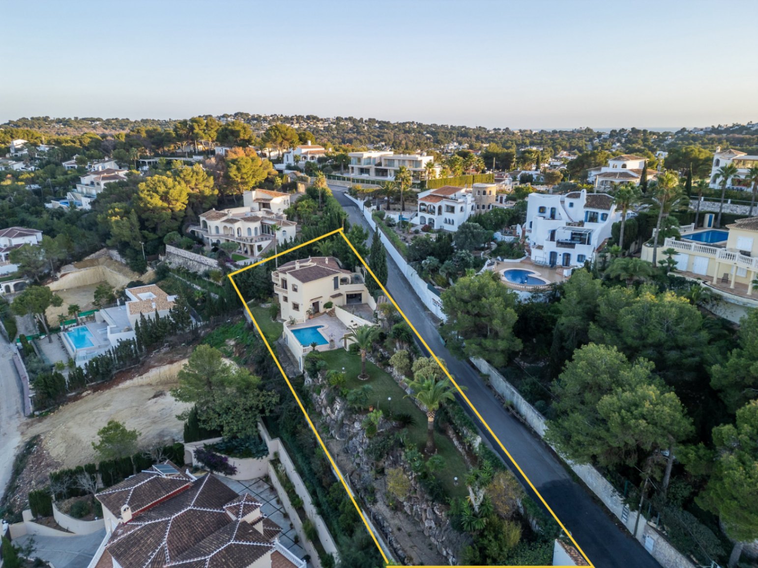 Aerial view of the outlined property featuring the Mediterranean villa, private swimming pool, and terraced gardens with palm trees in Costa Nova.