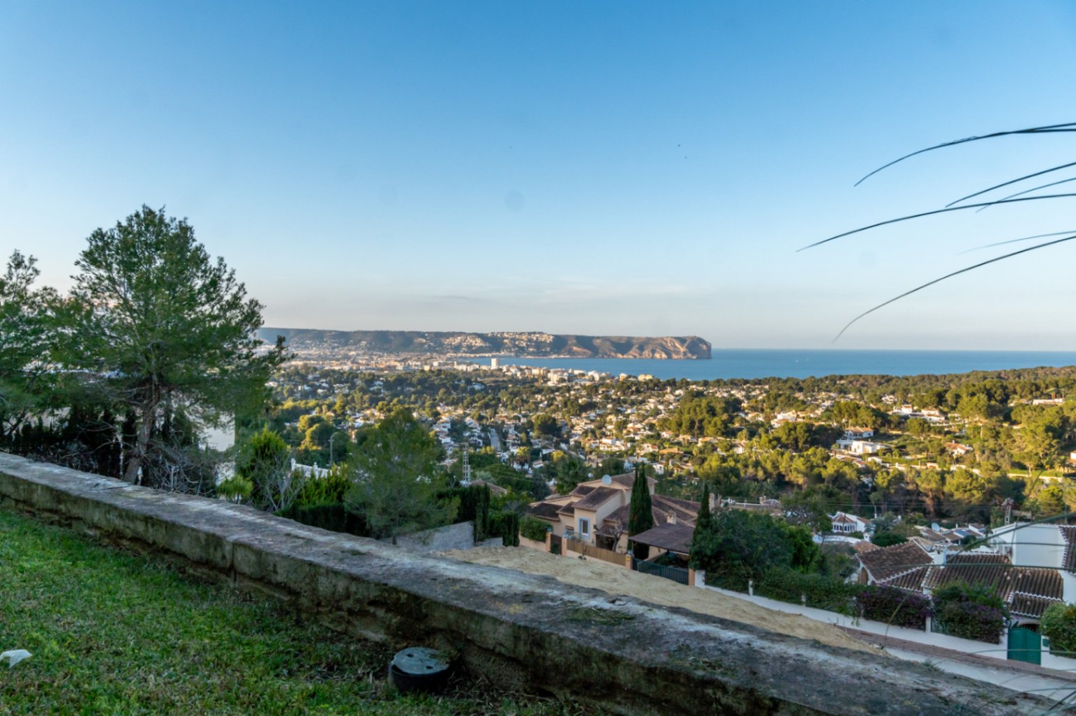 Panoramic views from the property overlooking Jávea Bay and Cabo San Antonio, framed by Mediterranean greenery and native pine trees.