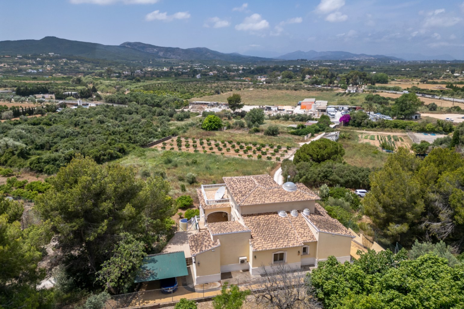 Aerial perspective of the villa featuring its traditional tiled roof, central glass dome, and circular skylights, set against a backdrop of valley and mountain views.