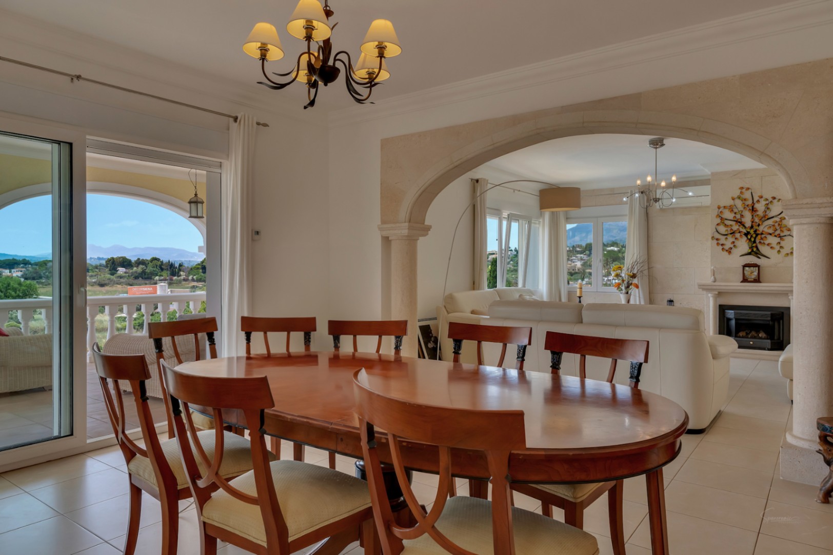 Bright dining area with a wooden table, connected to the living room via a Tosca stone archway, featuring direct access to the terrace and valley views.