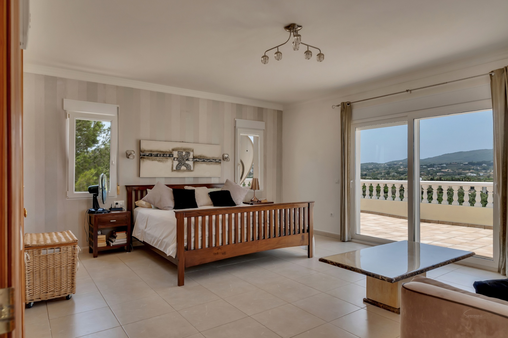 Master bedroom featuring a wooden bed frame, striped accent wall, and large sliding doors opening onto a private terrace with expansive valley views.